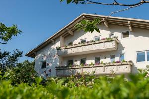a building with a balcony with flowers on it at Pension Etschland in Tirolo