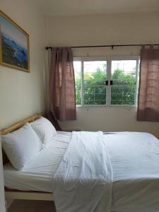 a bedroom with a large white bed with a window at Baan Aomjai in Prachuap Khiri Khan