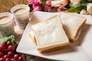 a sandwich on a white plate with grapes and cups of coffee at Hua Jia Motel in Tainan