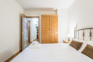 - une chambre avec un lit blanc et une armoire en bois dans l'établissement Apartamento Refugi, à Canillo