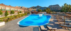 a pool at a resort with chairs and mountains in the background at Anavadia Hotel-All Inclusive in Kolymbia