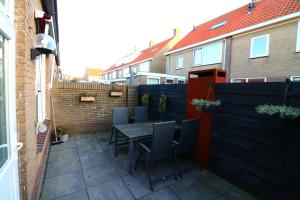 a patio with a table and chairs and a fence at Renovated Beach House in Egmond aan Zee