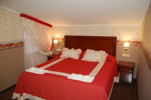 a bedroom with a red bed with red sheets and pillows at Готель Баварія in Poltava