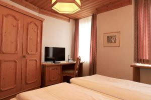 a bedroom with two beds and a desk with a television at Hotel-Restaurant Weisses Kreuz in Breitenbach