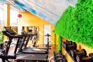 a gym with a green wall with tread machines at Fivitel Hoi An Hotel in Hoi An