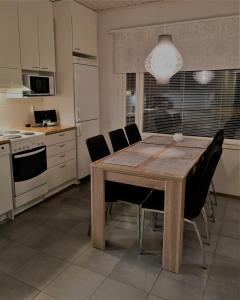 a kitchen with a wooden table and black chairs at Vuokatin Lumo in Vuokatti