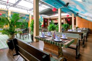 a dining room with tables and chairs and plants at Fivitel Hoi An Hotel in Hoi An