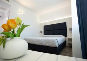 a bed room with a white bedspread and a white vase with flowers at DOLCE LAGUNA 2 in Tessera
