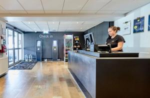 a woman standing at a cash counter in a store at Zleep Hotel Aarhus Viby in Aarhus