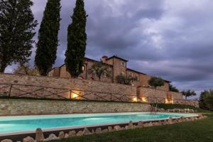 un domaine avec une piscine en face d'un mur dans l'établissement Il Castro Luxury Apartments, à San Gimignano