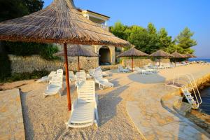 eine Gruppe von Stühlen und Sonnenschirmen am Strand in der Unterkunft Depadansa Hotel Lucija*** in Posedarje