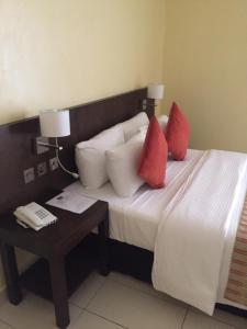 a bedroom with a bed with red pillows and a table at AMOR Hotel Ekiti in Ado Ekiti