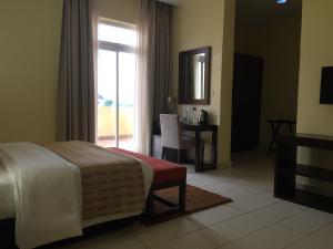 Schlafzimmer mit einem Bett, einem Schreibtisch und einem Fenster in der Unterkunft AMOR Hotels Ekiti in Ado Ekiti