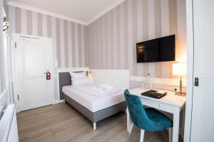 a bedroom with a bed and a desk with a computer at Hotel IV Jahreszeiten Kühlungsborn in Kühlungsborn +72 photos