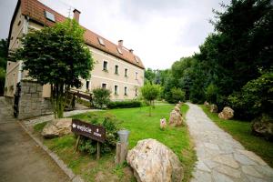 un jardín con rocas, un edificio y un cartel en Ślężański Młyn, en Szczepanów