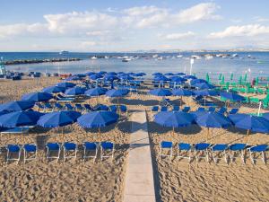 a group of blue umbrellas and chairs on a beach at Hotel La Villarosa Terme in Ischia