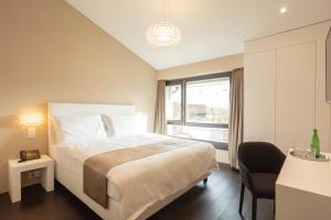 sypialnia z dużym białym łóżkiem i oknem w obiekcie Hotel Lo! im Kreuz Jona w mieście Rapperswil-Jona