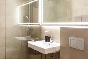 W łazience znajduje się biała umywalka i lustro. w obiekcie Hotel Lo! im Kreuz Jona w mieście Rapperswil-Jona
