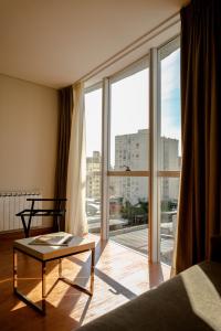 - un salon avec une table et une grande fenêtre dans l'établissement Sofia Soberana Hotel Boutique, à Bahía Blanca