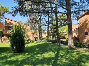 a green yard with trees and a building at Azur Apartment Sirmione in Sirmione