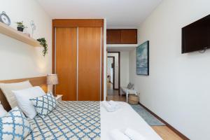 1 dormitorio con 1 cama con almohadas azules y blancas en Deluxe Bright Flat with Netflix by Host Wise, en Oporto