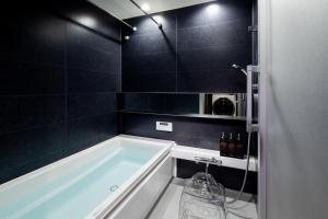 a bath tub in a bathroom with black tiles at SKY KYOTO in Kyoto +40 photos
