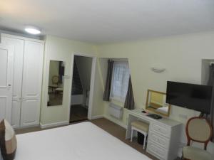 a bedroom with a bed and a desk and a television at Beau Rivage in St Brelade