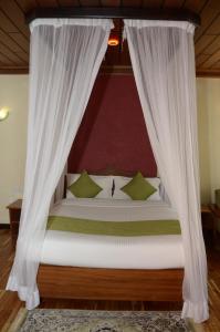 a bed with a white canopy with green pillows at The Noble Hotel & Conference Centre in Eldoret
