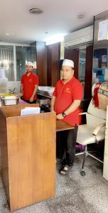 Zwei Männer standen an einem Schreibtisch in einem Büro. in der Unterkunft Asia Hotel in Riad