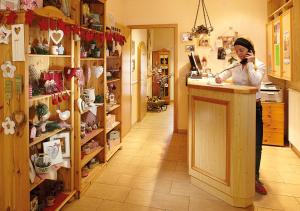 une femme debout au comptoir d'un magasin parlant sur un téléphone portable dans l'établissement Pension zur Kurfürstin, à Wolkenstein