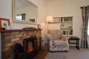 a living room with a fireplace and a chair and a mirror at Darroch Beag in Saint Catherines