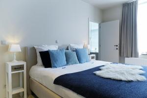 ein Schlafzimmer mit einem großen Bett mit blauen und weißen Kissen in der Unterkunft Jeanne in Nieuwpoort