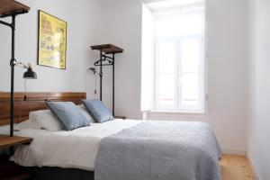 a bedroom with a bed with blue pillows and a window at Lisbon Poets Inn in Lisbon