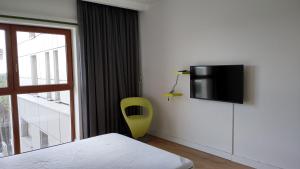 a bedroom with a yellow chair and a tv on the wall at Baltic Beach View Porta Mare plaża in Dziwnówek