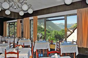 un comedor con mesas blancas y una gran ventana en Hotel Garona en Salardú