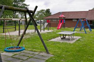 - un parc avec une aire de jeux dotée d'une table et de balançoires dans l'établissement KNAUS Campingpark Eckwarderhörne, à Eckwarderhörne