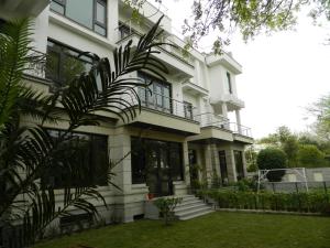 a white house with a balcony and a yard at 76 Friends Colony in New Delhi