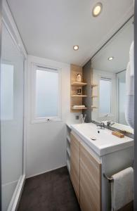 La salle de bains est pourvue d'un lavabo et d'un grand miroir. dans l'établissement KNAUS Campingpark Eckwarderhörne, à Eckwarderhörne