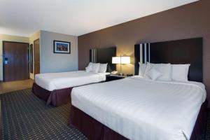 duas camas num quarto de hotel com lençóis brancos em Ramada by Wyndham Glendale Heights/Lombard em Glendale Heights