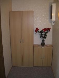 ein Schrank mit einer Vase mit roten Blumen darin in der Unterkunft Ferienwohnung Böhnstedt in Thale