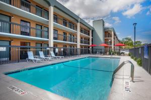 a pool in front of a hotel with chairs and umbrellas at Quality Inn West Fort Worth in Fort Worth