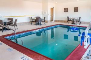una piscina con sillas y mesas en una habitación de hotel en Comfort Inn near Frost Bank Center en San Antonio