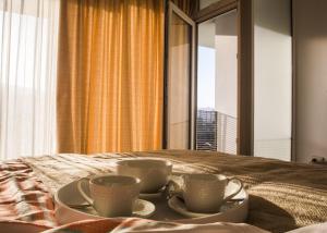 two cups and saucers on a bed in front of a window at Loftbellavistavalparaiso in Valparaíso