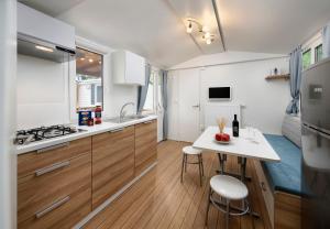 eine kleine Küche mit einer weißen Arbeitsplatte und einem Tisch in der Unterkunft KNAUS Campingpark Dorum in Dorum Neufeld
