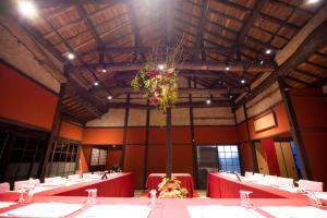une grande chambre avec des tables rouges et une plante dans l'établissement Kachusha Gekko, à Tadotsu
