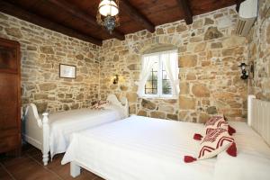 a bedroom with two beds and a stone wall at Villa Kamilari in Kamilari +64 photos