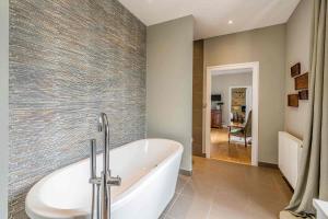 a bathroom with a tub and a tile wall at Manoir du Moulin in Sainte-Hermine +71 photos