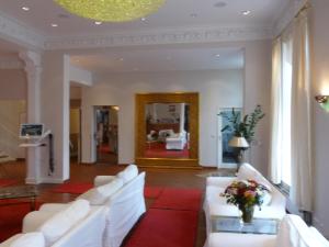 a living room with white couches and a red rug at Hotel Commodore in Hamburg