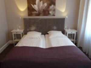 1 cama con 2 almohadas blancas y 2 mesas en Hotel Commodore en Hamburgo