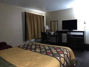 a hotel room with a bed and a desk and a television at Super 8 by Wyndham Germantown/Milwaukee in Germantown